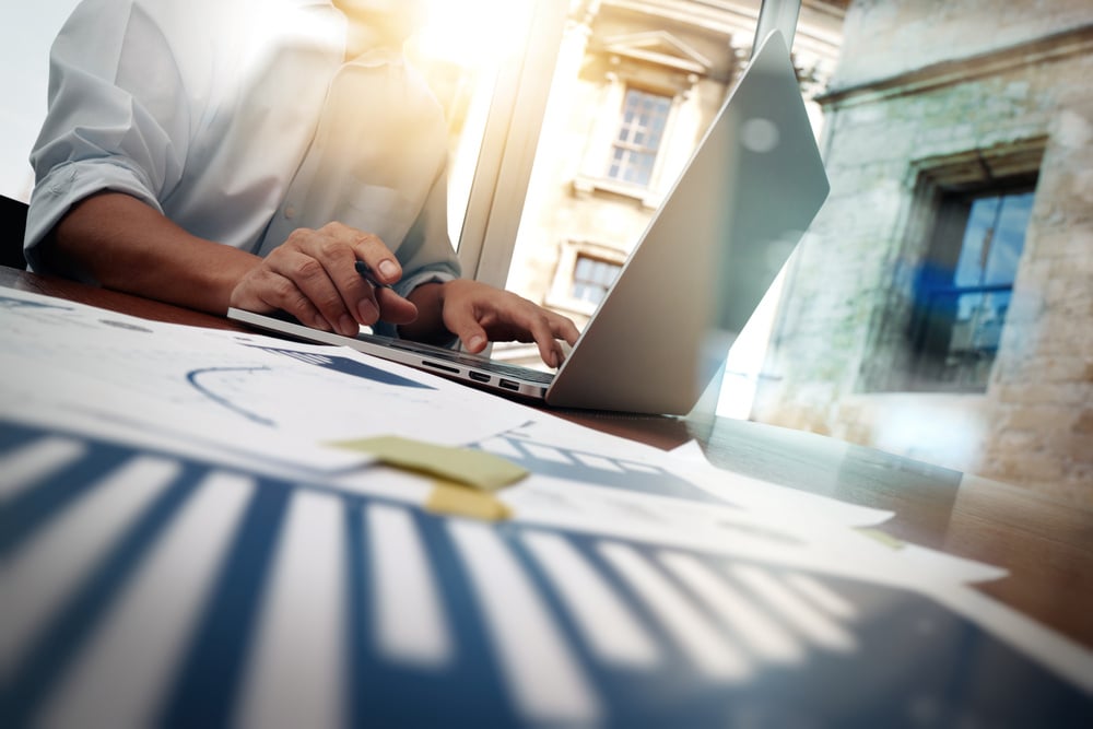 business documents on office table with smart phone and digital tablet and graph financial diagram and man working in the background business documents on office table with smart phone and digital tablet and graph financial diagram and man working in the background